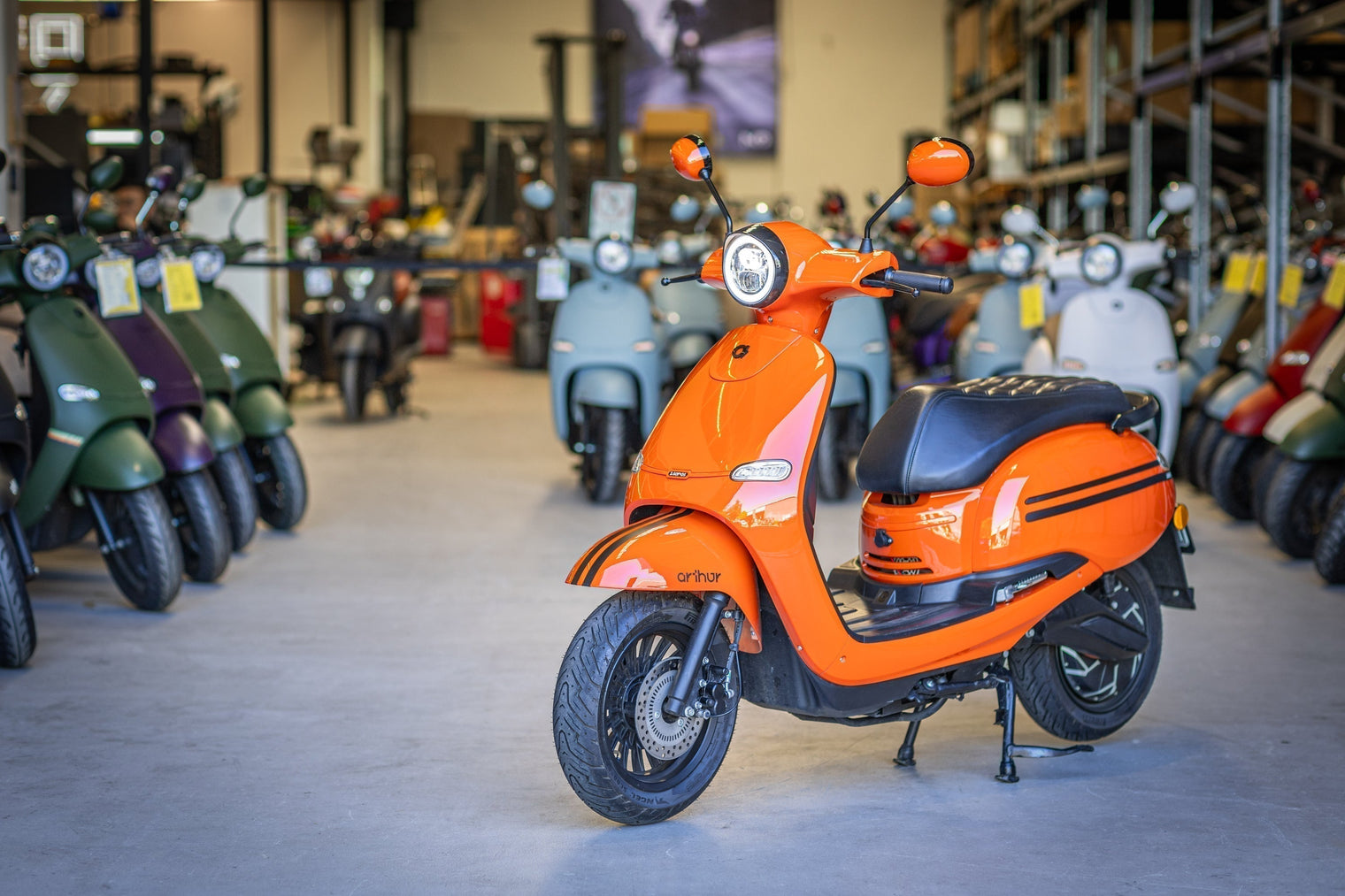 Orange FONZ Electric scooter sitting in warehouse with other scooters behind