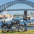 Load image into Gallery viewer, Person with Royal Enfield Bullet 350 by the water with Sydney Harbour  Bridge in the background
