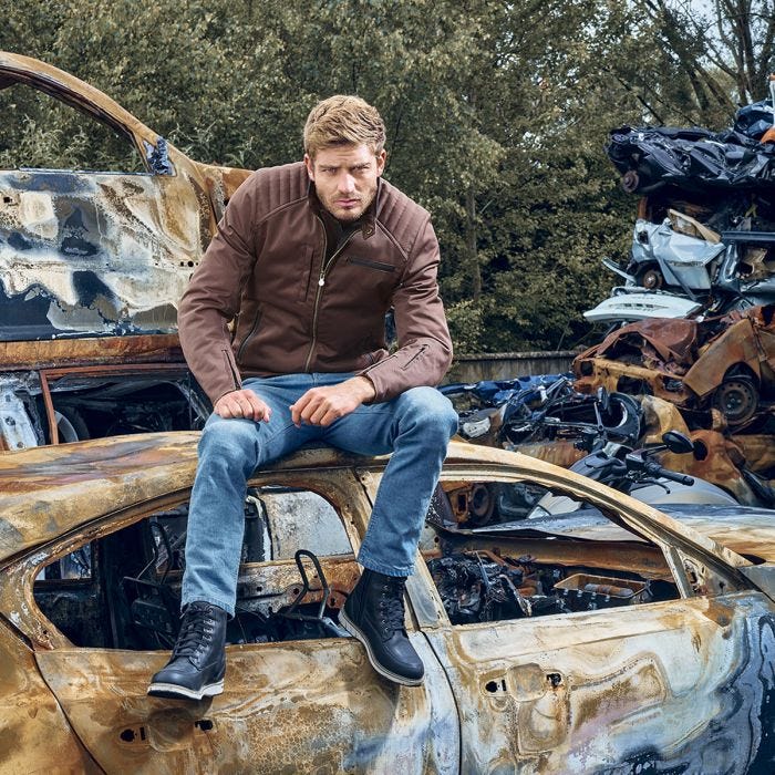 Man wearing Segura SEGURA ETERNAL MOTORCYCLE JACKET MAROON sitting on rusted car